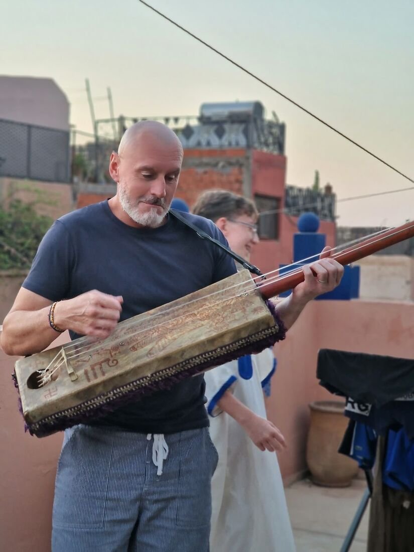 Musicien jouant du guembri au coucher du soleil