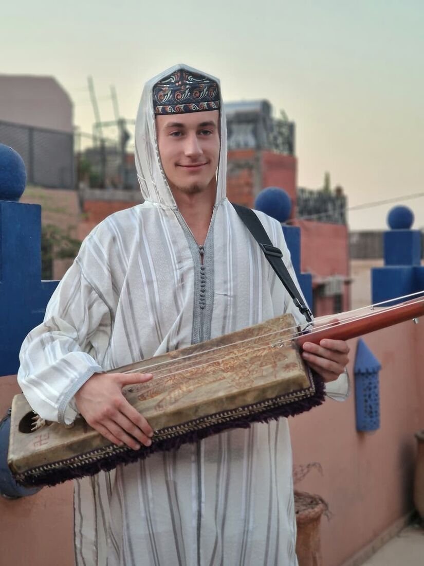Voyageuse essayant le guembri avec les musiciens